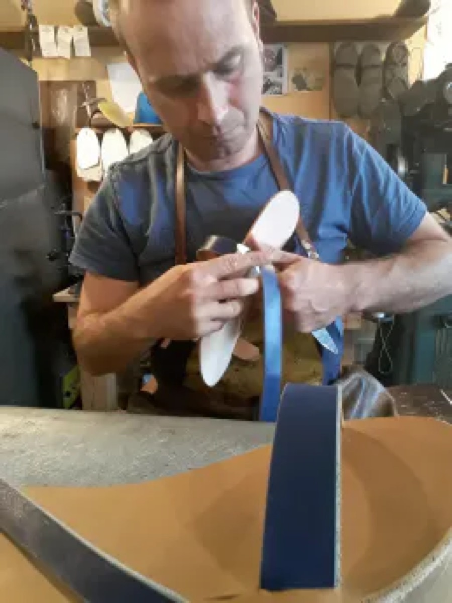 Artisan travaillant une pièce de cuir bleu à l'établi